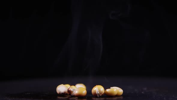 Smoke rising off popcorn seeds rolling on hot plate