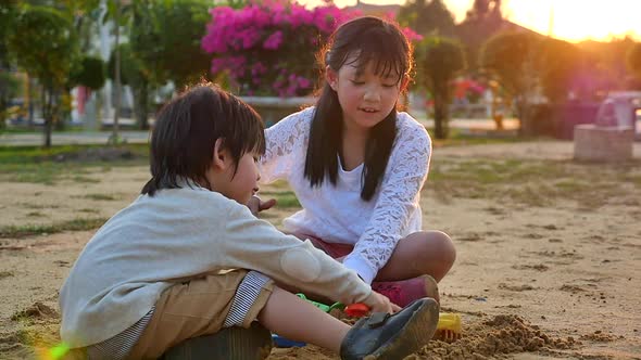 Asian Children Playing Sand In Playground Under Sunset