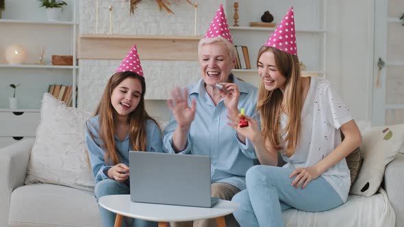 Cute Child Daughter Young Adult Mother and Old Grandma Looking at Laptop Screen Wearing Party Hats