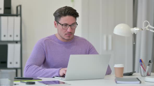 Middle Aged Man Working on Laptop in Office 