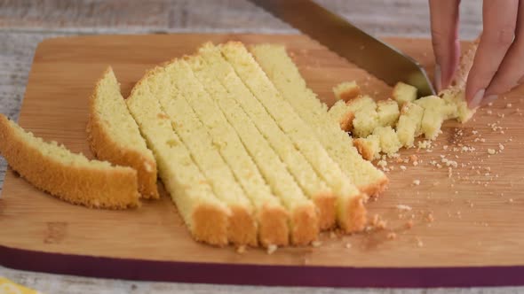 Women pastry chef cuts biscuit dough into small pieces.	