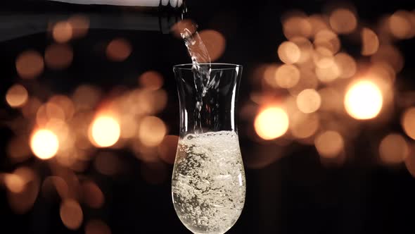 Pouring champagne in flute with sparklers fireworks lights on black background. Christmas celebratio