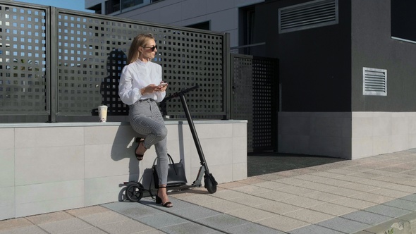 Businesswoman with mobile and her scooter next