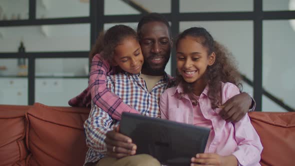 African Dad with Daughters Using Tablet Pc on Couch