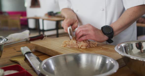 Caucasian male chef kutting meat on a kitchen table