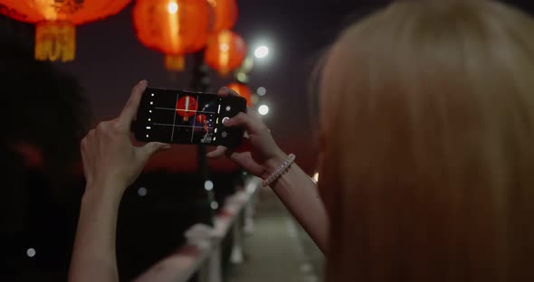 Young Asian girl take a photo of Chinese lantern by mobile phone in Chinese new year holiday.