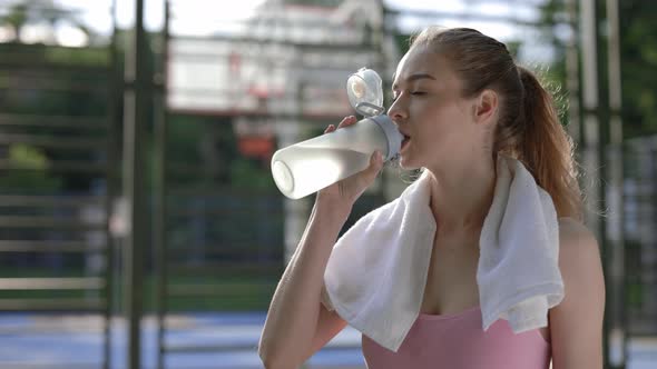 Side View of Yoga Woman Drinking Water From the Sport Bottle Carris the Towel on Her Neck on the