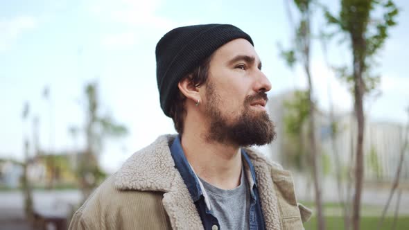 Handsome bearded man wearing hat walking and smoking