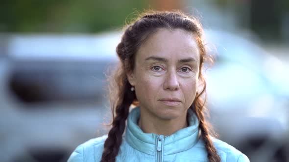 Portrait of a Middleaged Brunette with Long Braids on a Sunny Day