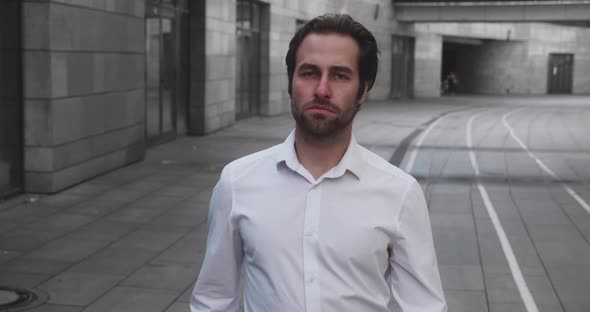 Young Stylish Bearded Business Man Walks Down Business District in White Shirt on Urban Background