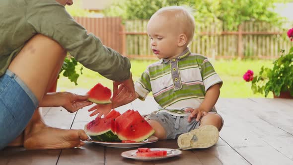 Mom Taking Out Seeds From Watermelon and Giving a Slice to Her Baby Boy