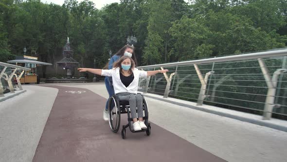 Daughter Driving Mother on Wheelchair Along Bridge