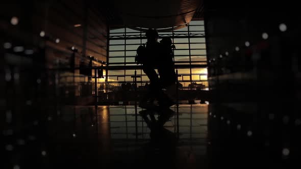 Silhouette of Man and a Woman They Say Goodbye in Airport Terminal