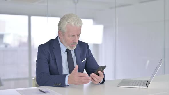 Upset Old Businessman Reacting to Failure on Smartphone