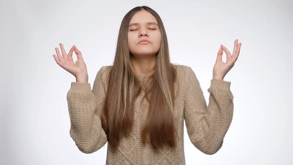 Portrait of Girl Calming Down and Making Meditation Gesture Over White Background