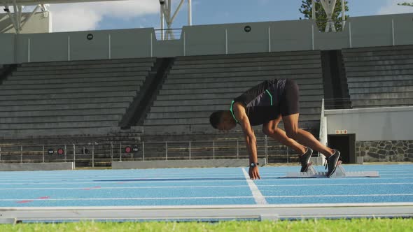 Side view of mixed race athlete preparing for race in stadium