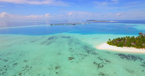 Aerial drone view of scenic tropical island and resort hotel with overwater bungalows in Maldives