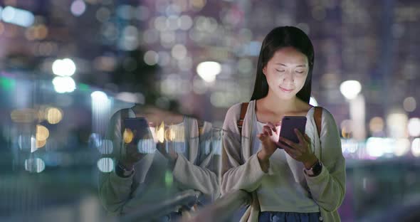 Woman use of mobile phone in city at night