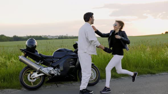 Beautiful Couple Meets Near Sport Motorcycle on the Road Near Field