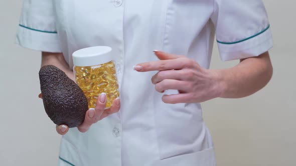 Nutritionist Doctor Holding Organic Avocado Fruit and Jar of Medicine or Vitamin or Omega 3 Capsules