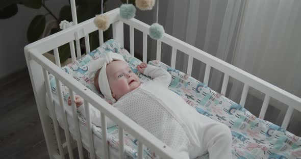 Portrait of a Cute Newborn Baby Lying in the Cradle Looking at Spinning Toys