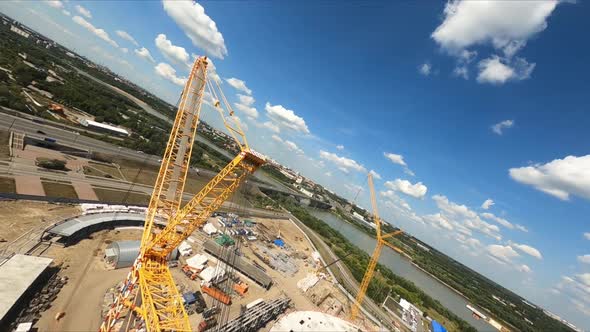 Yellow Tower Crane Lifts Freights Near Stadium Building