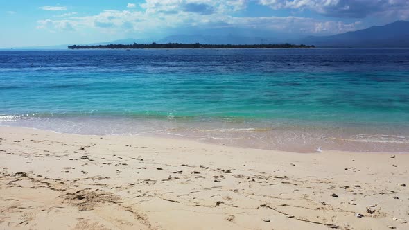 Tropical beach with white sand mountains in the background