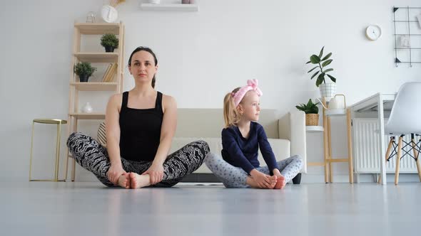 Mother with Daughter Practicing Yoga at Home