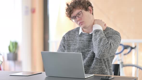 Young Man with Neck Pain Using Laptop at Work 