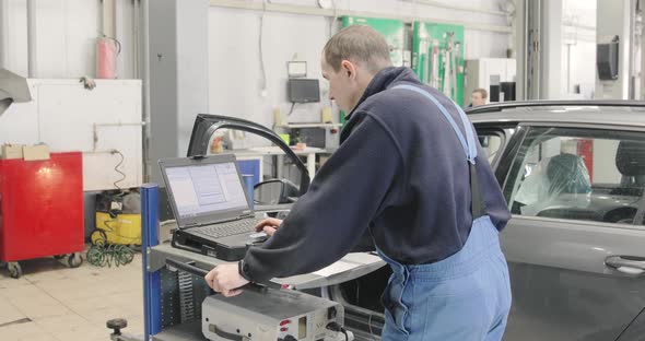 Mechanic Is Working In Repair Shop. Computer Diagnostics Car Engine In Service