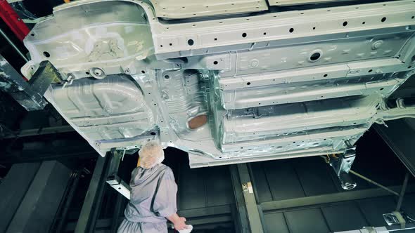 Car Factory Worker Applying Chemical Solution on a Car Bottom