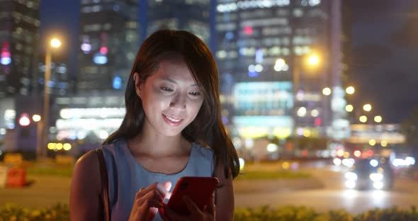 Woman use of mobile phone in the city at night