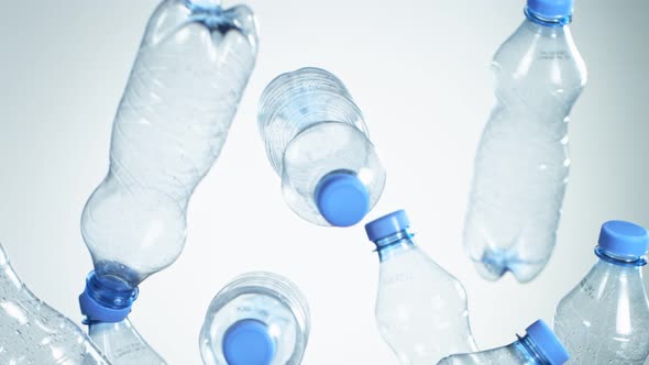 Super Slow Motion Shot of Flying Empty Plastic Bottles on Light Blue Gradient Background at 1000Fps