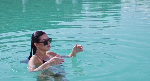 Happy Woman in Sunglasses and Bikini Swimming in Pool