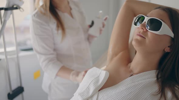 Adult Woman During Modern Laser Hair Removal Treatment in Clinic Aesthetician is Applying Gel in