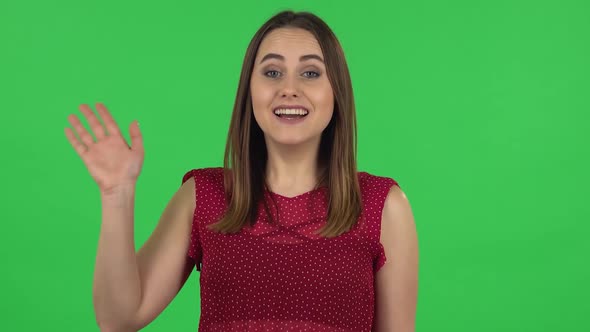 Portrait of Tender Girl in Red Dress Is Waving Hand and Showing Gesture Come Here. Green Screen