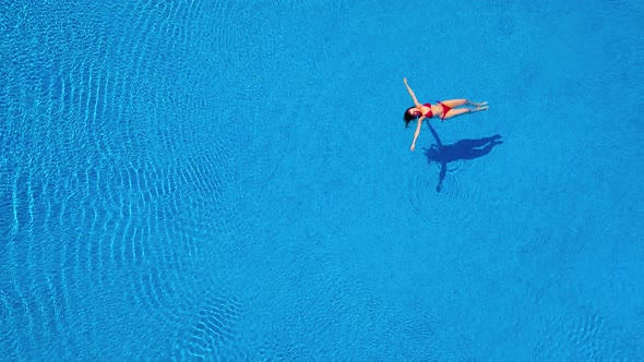 View From the Top As a Woman in a Red Swimsuit Lying on Her Back in the Pool