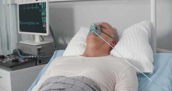 Elderly Person with Oxygen Mask Lying in Hospital Bed