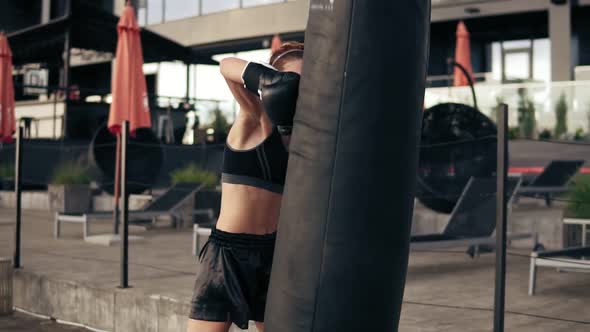 Attractive Athletic Female Boxer in Gloves Exercising with a Bag