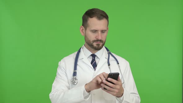 Young Doctor Using Mobile Phone Against Chroma Key