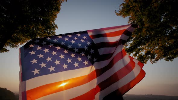 Back View of Happy Woman with USA National Flag Standing Outdoors at Sunset