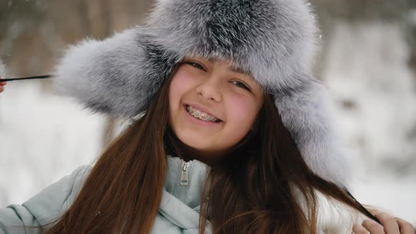 Winter Portrait of a Cheerful Teenage Girl in a Fur Hat