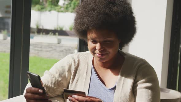 Video of happy plus size african american woman using two smartphones