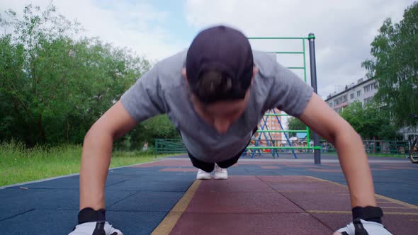 Young Guy Performs Pushup Exercises on the Street a Sports Ground