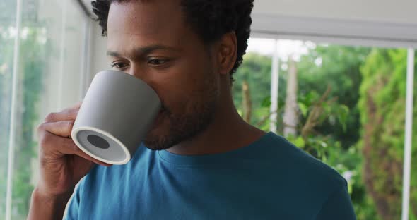 Relaxed biracial man drinking coffee, smiling and looking into distance