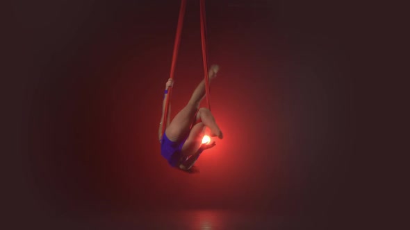Beautiful Aerialist Girl Doing Acrobatic and Flexible Tricks on Red Aerial Silks Tissues on Red