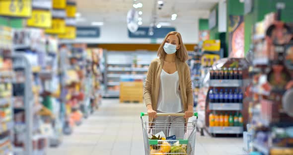 Young Woman Carries a Cart with Groceries in the Supermarket, Shopping for Groceries During the