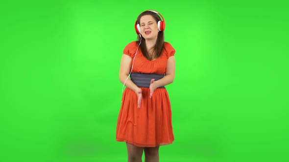 Cute Girl Is Dancing and Enjoying Music in Big Red Headphones. Green Screen