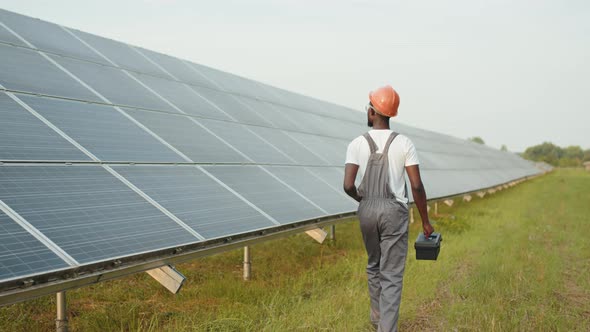 Energy Engineer with Instruments Walking on Solar Farm