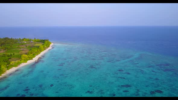 Aerial drone shot nature of idyllic seashore beach vacation by blue water with bright sandy backgrou